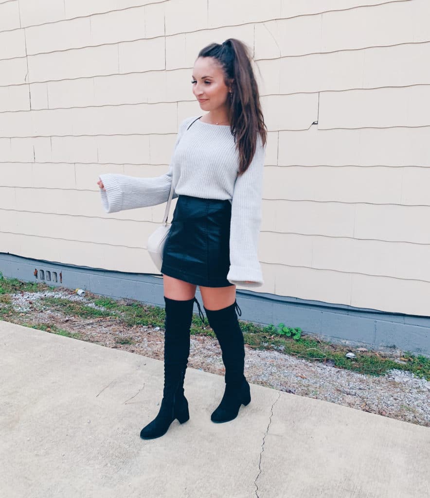 grey bell sleeve sweater with a faux leather skirt and over the knee boots