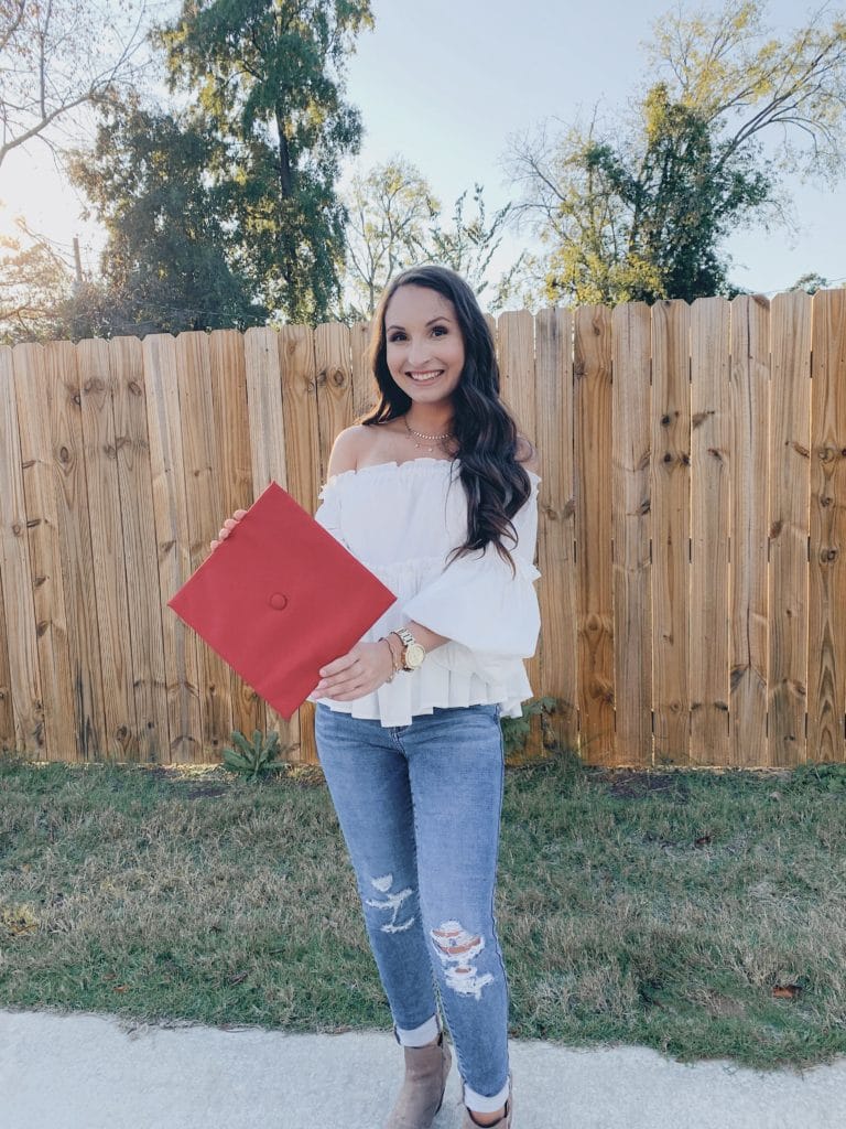 red graduation cap and white off the shoulder ruffle top and ripped jeans