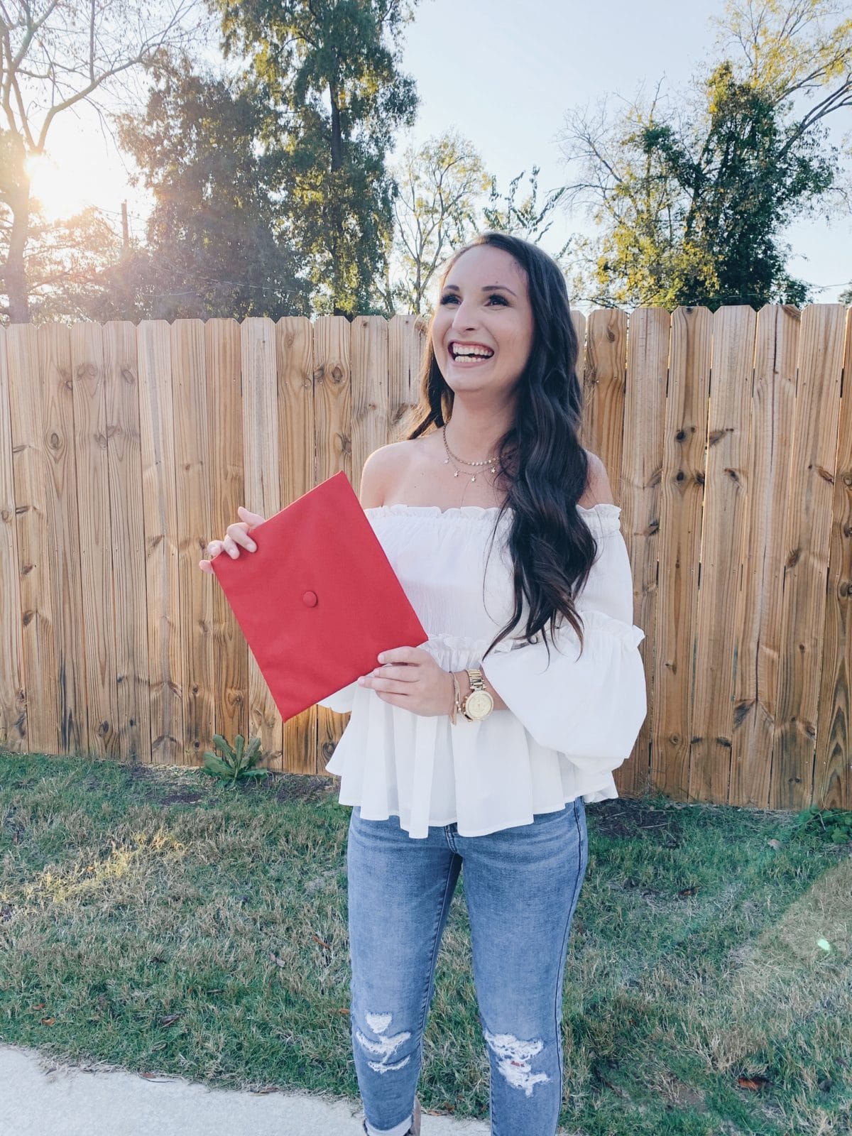 white off the shoulder ruffle top and red graduation cap university of alabama